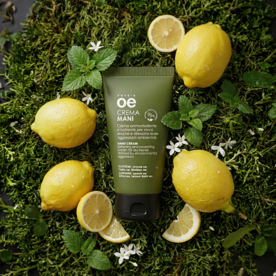 immagine crema mani ambientata su sfondo verde naturale circondata da Limoni e altri elementi naturali 